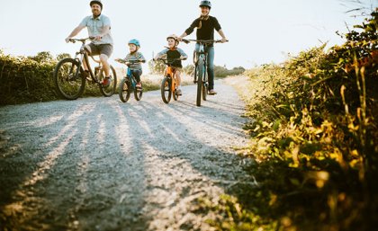 Man and woman on bikes flanking two small children on bikes 